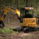 Cat® 303.5 mini hydraulic excavator at work in a wooded construction site, representing high-performance excavator rental in Seattle for diverse project needs.