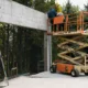 Construction workers operating a 25 ft scissor lift at a job site surrounded by trees, representing a reliable 25 ft scissor lift rental in Seattle offered by Williams Diesel LLC