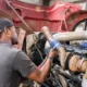 Technician performing mobile diesel repair in Seattle on a heavy-duty truck engine at a commercial service site.