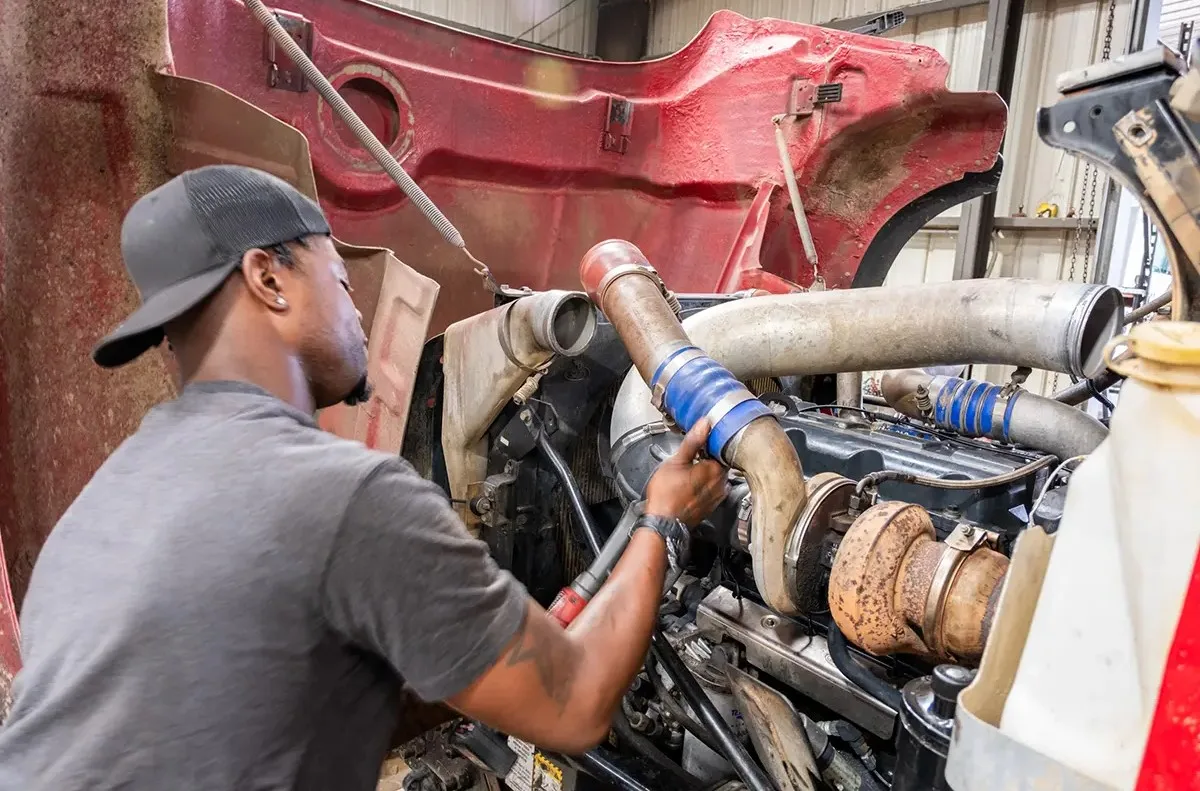 Technician performing mobile diesel repair in Seattle on a heavy-duty truck engine at a commercial service site.