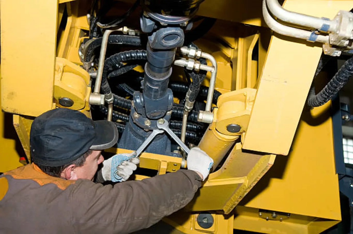 Technician performing hydraulic maintenance on a construction machine during heavy equipment repair in Seattle.