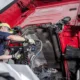 Mobile diesel truck repair service in Seattle with a skilled mechanic inspecting and repairing the engine of a heavy-duty red truck for reliable roadside assistance.