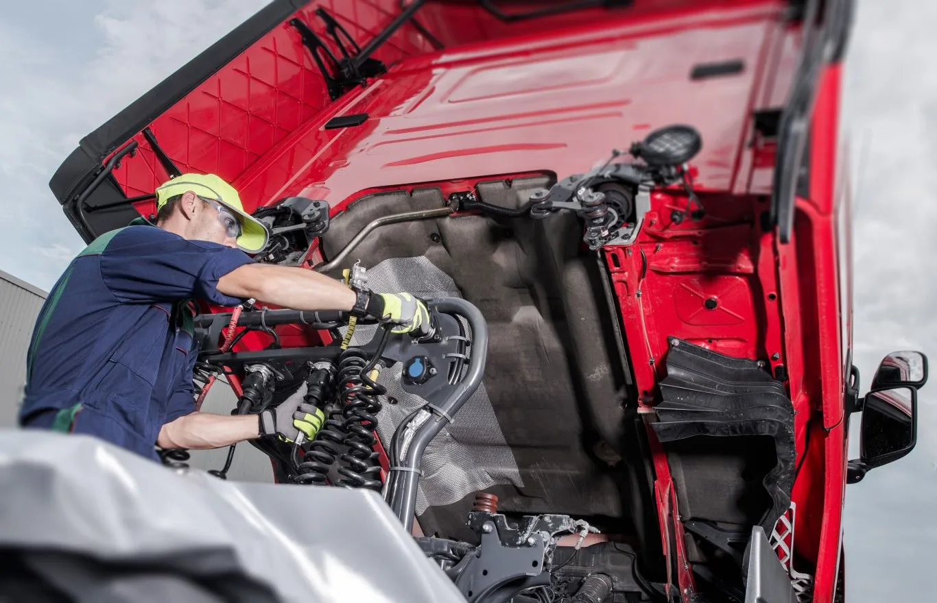 Mobile diesel truck repair service in Seattle with a skilled mechanic inspecting and repairing the engine of a heavy-duty red truck for reliable roadside assistance.