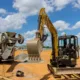 Construction equipment rental in Seattle with a compact excavator and cement truck working on a building site under a clear sky.