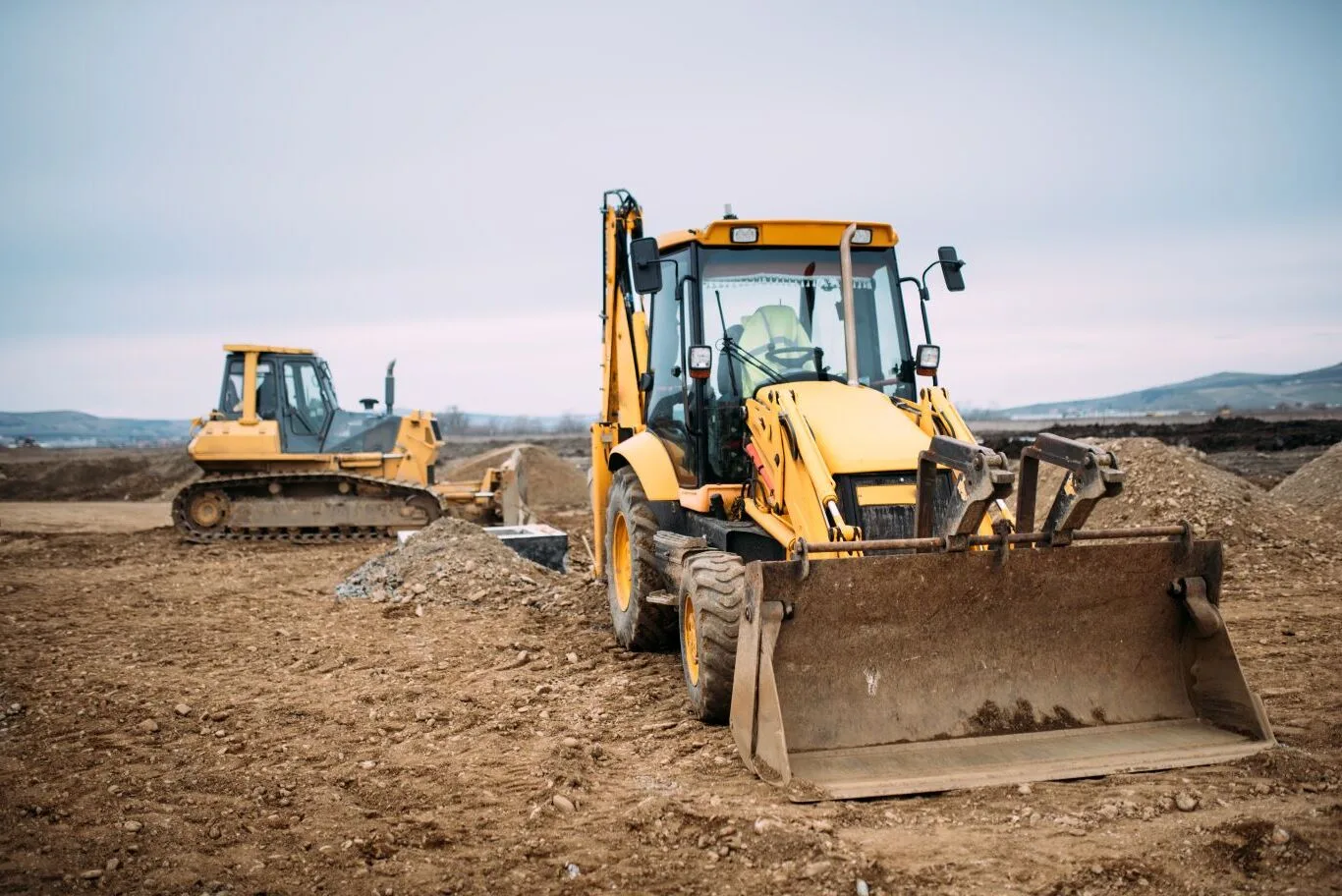 Yellow construction vehicles on a worksite representing heavy machinery available through commercial equipment rental services