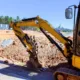 Yellow construction equipment at a worksite showing a digging arm used for mini excavator attachments rental services.