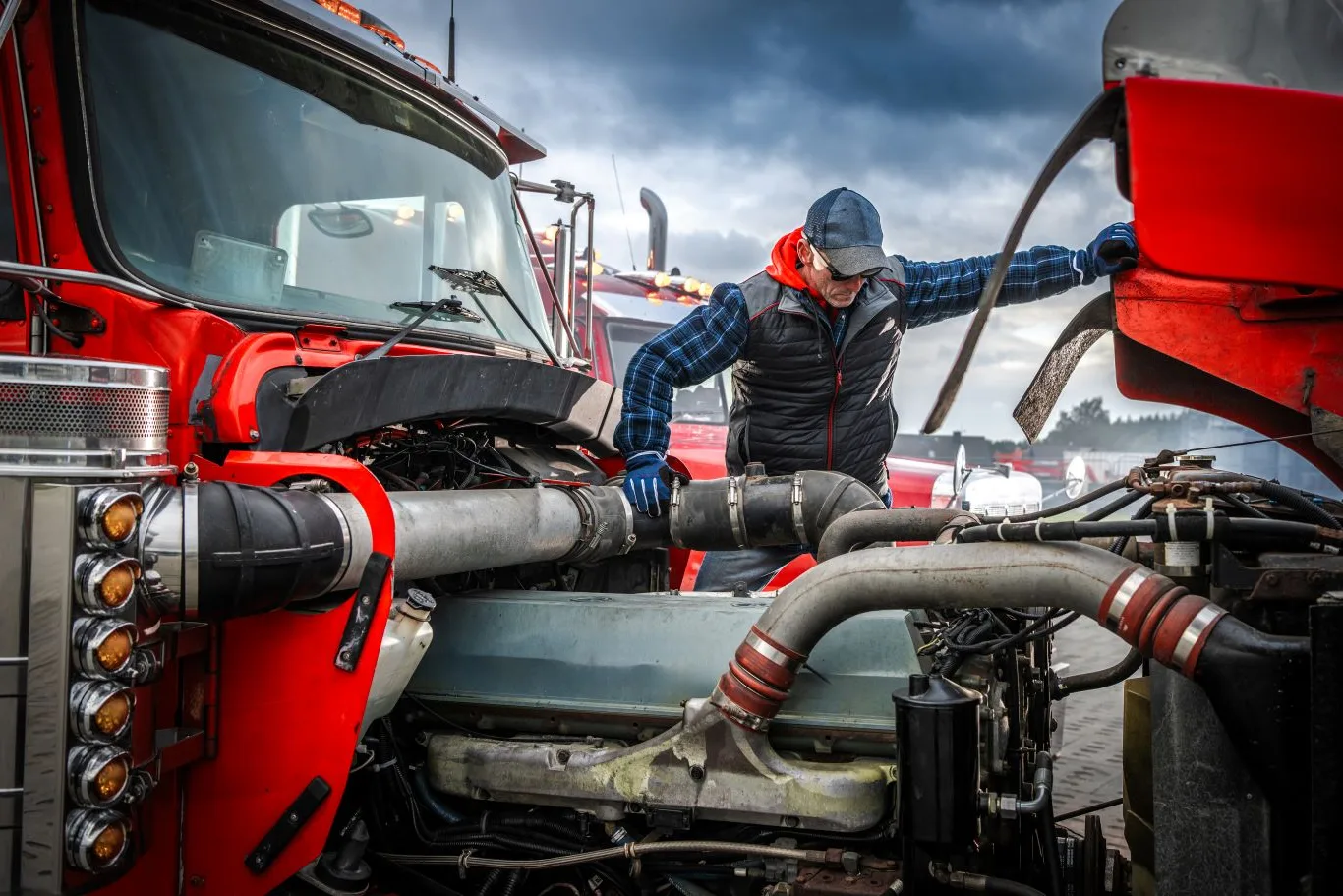 A mobile truck mechanic performing on-site diesel engine inspection and repair on a heavy-duty red truck, ensuring reliable roadside service and minimal downtime.