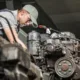 A skilled mechanic working on a large diesel engine inside a diesel repair shop