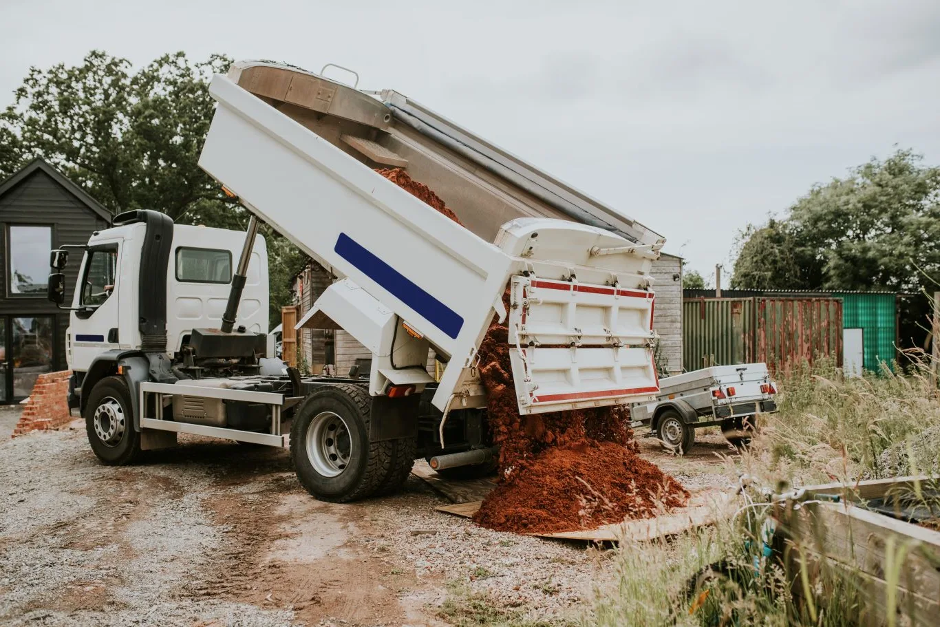 Dump trailer rental being used on a residential cleanup site, unloading soil and debris efficiently to support landscaping and construction work.