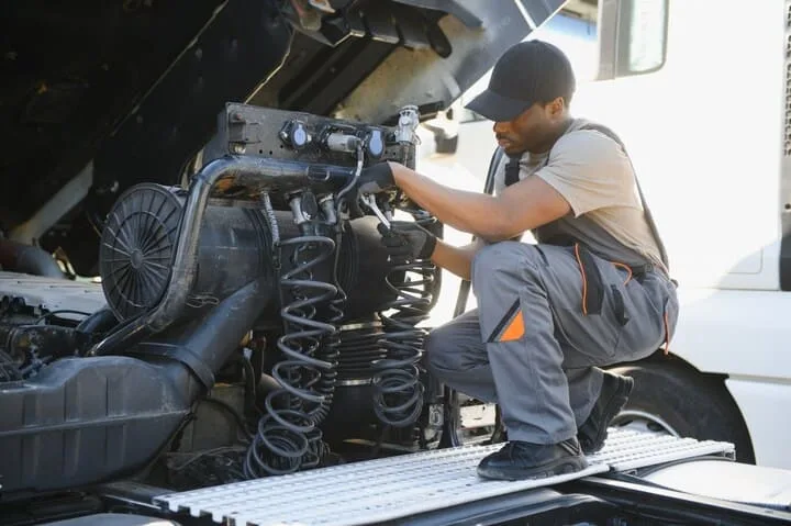 A skilled semi truck mechanic working under the hood of a large truck