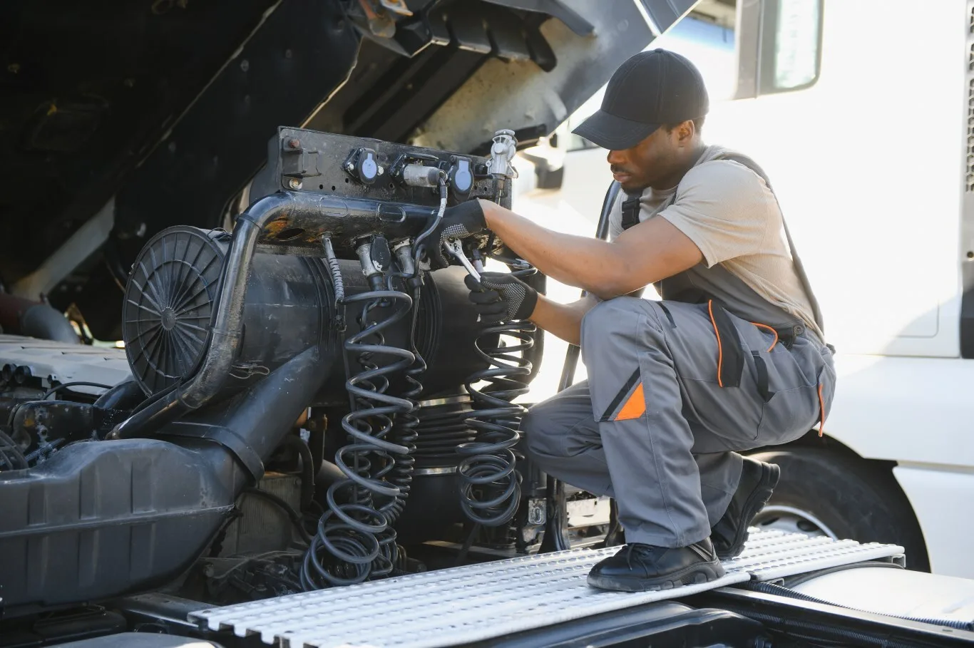 A skilled semi truck mechanic working under the hood of a large truck.
