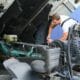 Mechanic inspecting a truck engine while performing diesel engine upgrades to improve performance and efficiency in a professional repair workshop.