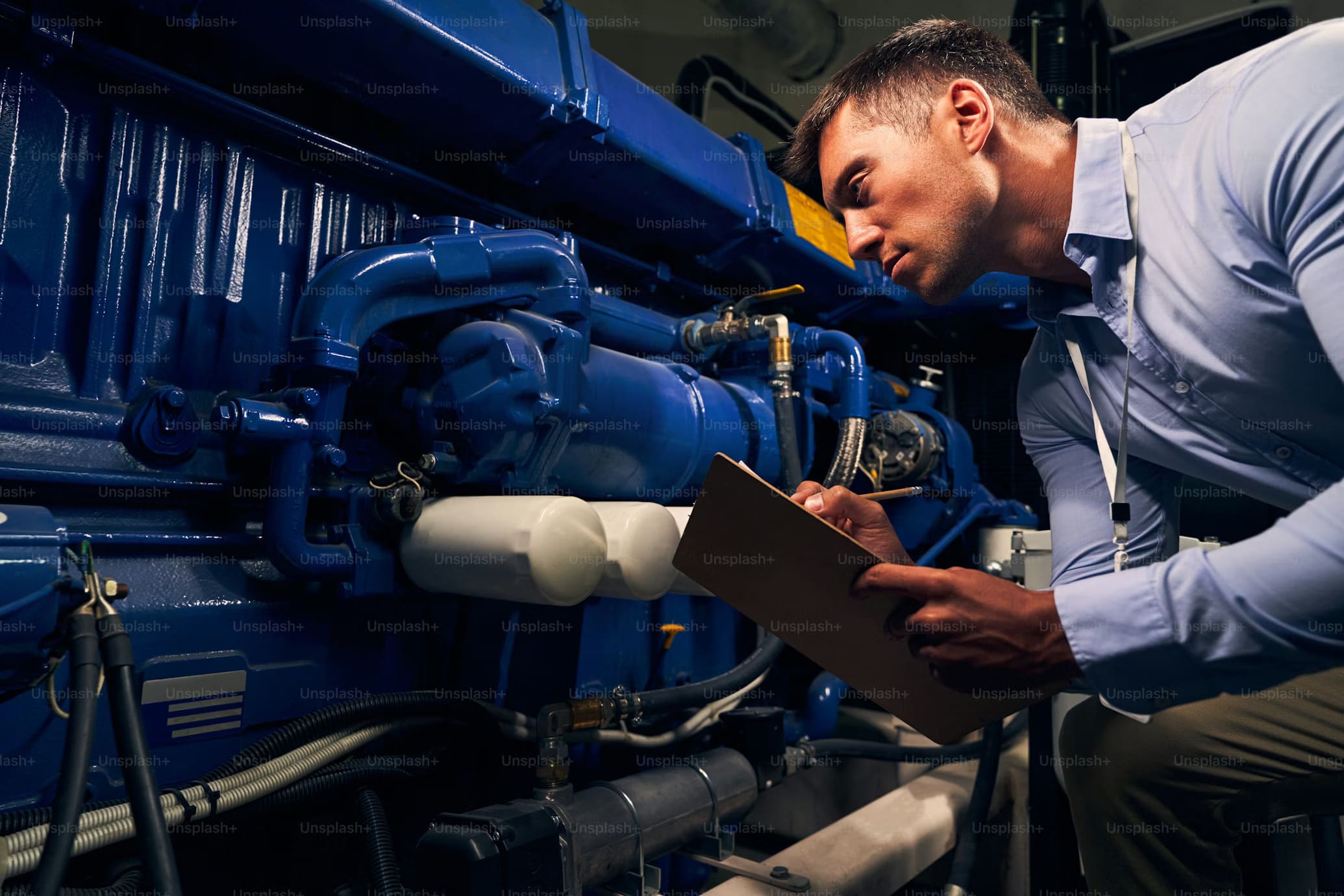 Technician inspecting a diesel engine and recording notes, demonstrating how diesel machine works to improve equipment performance and reliability.