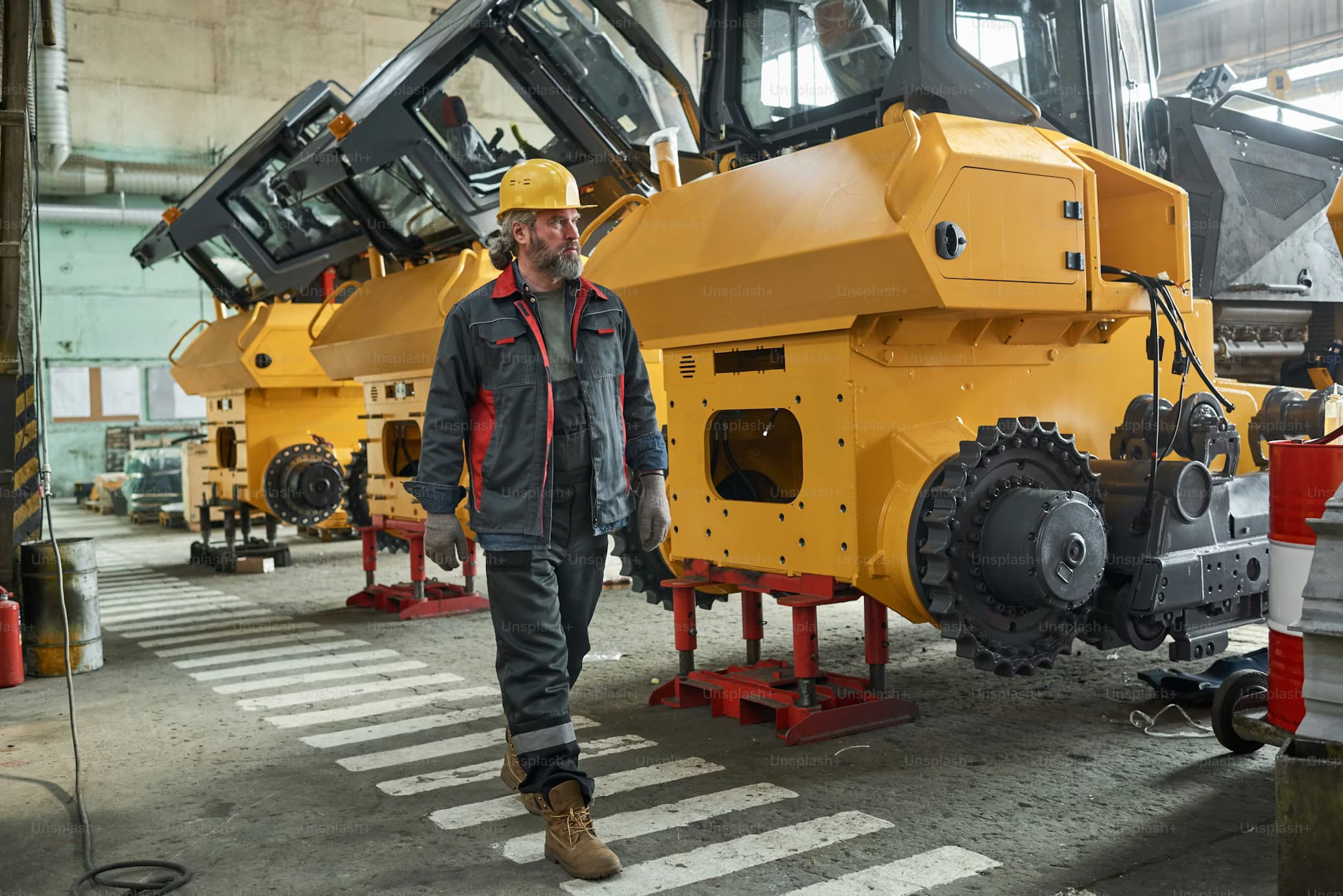 Technician walking through a workshop with heavy machinery, representing Williams equipment rental services for reliable construction equipment in Eatonville.