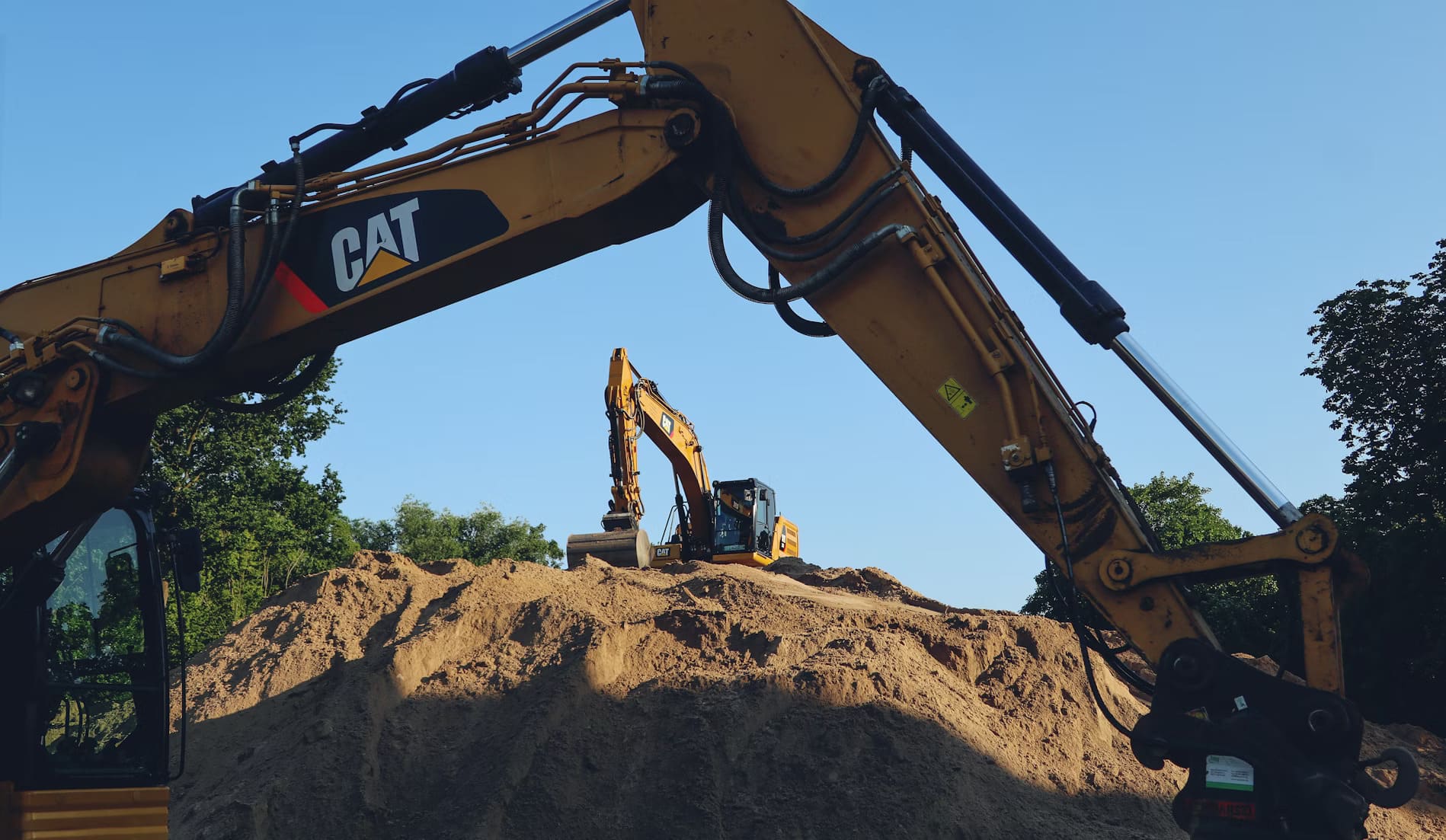 A well-maintained cat mini excavator with its boom extended, showcasing the clean hydraulic cylinders and greased pivot points on a professional construction site.