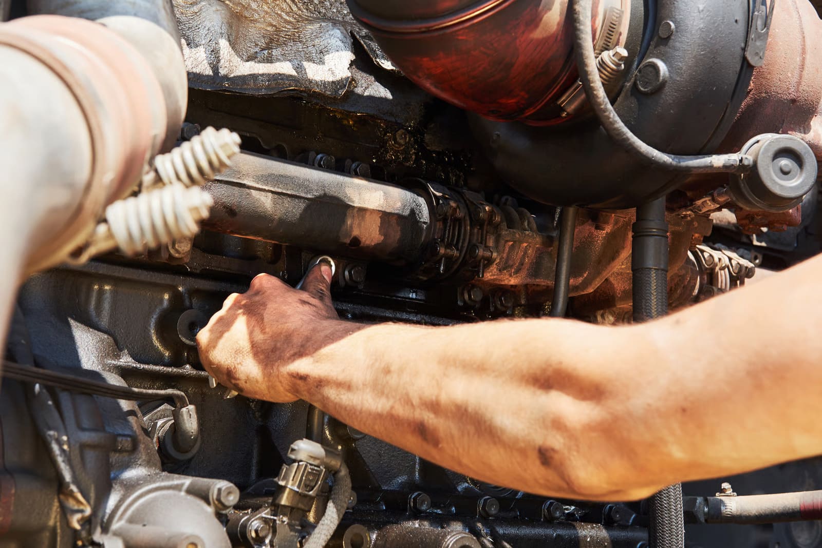 A heavy-duty technician performing systematic troubleshooting and component cleaning for small diesel engine repair on a compact utility powertrain inside a service center.