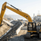 A heavy-duty long reach excavator for rent safely grading a steep shoreline embankment from a stable position far back from the unstable edge.